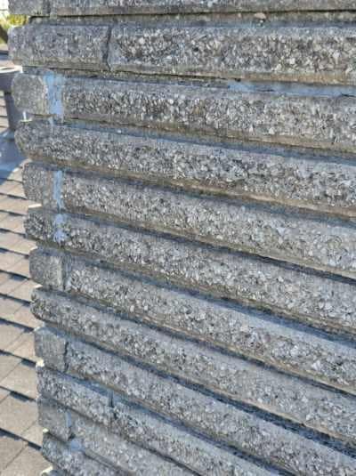 Close-up of a weathered, textured gray stone column with horizontal grooves, outdoors.