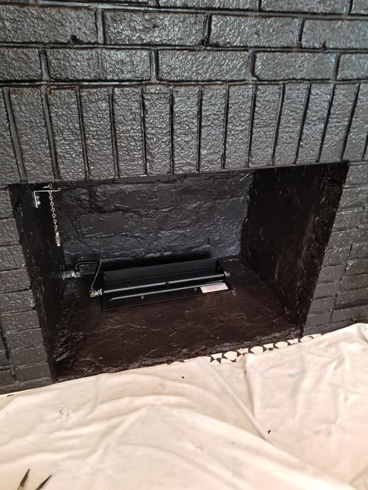 Black painted brick fireplace with a black interior. A black grate is visible inside.