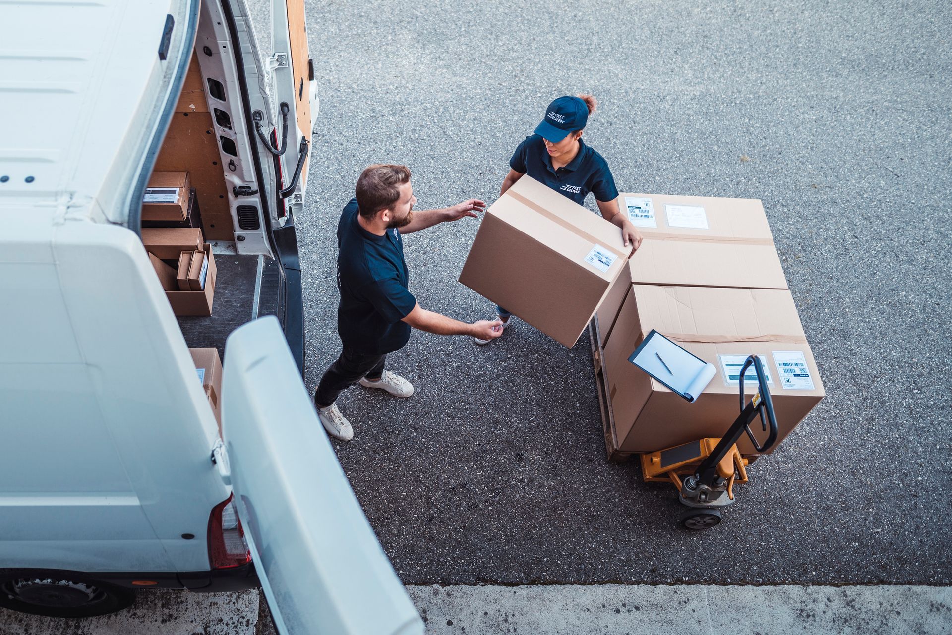A man is handing a box to another man in front of a van.