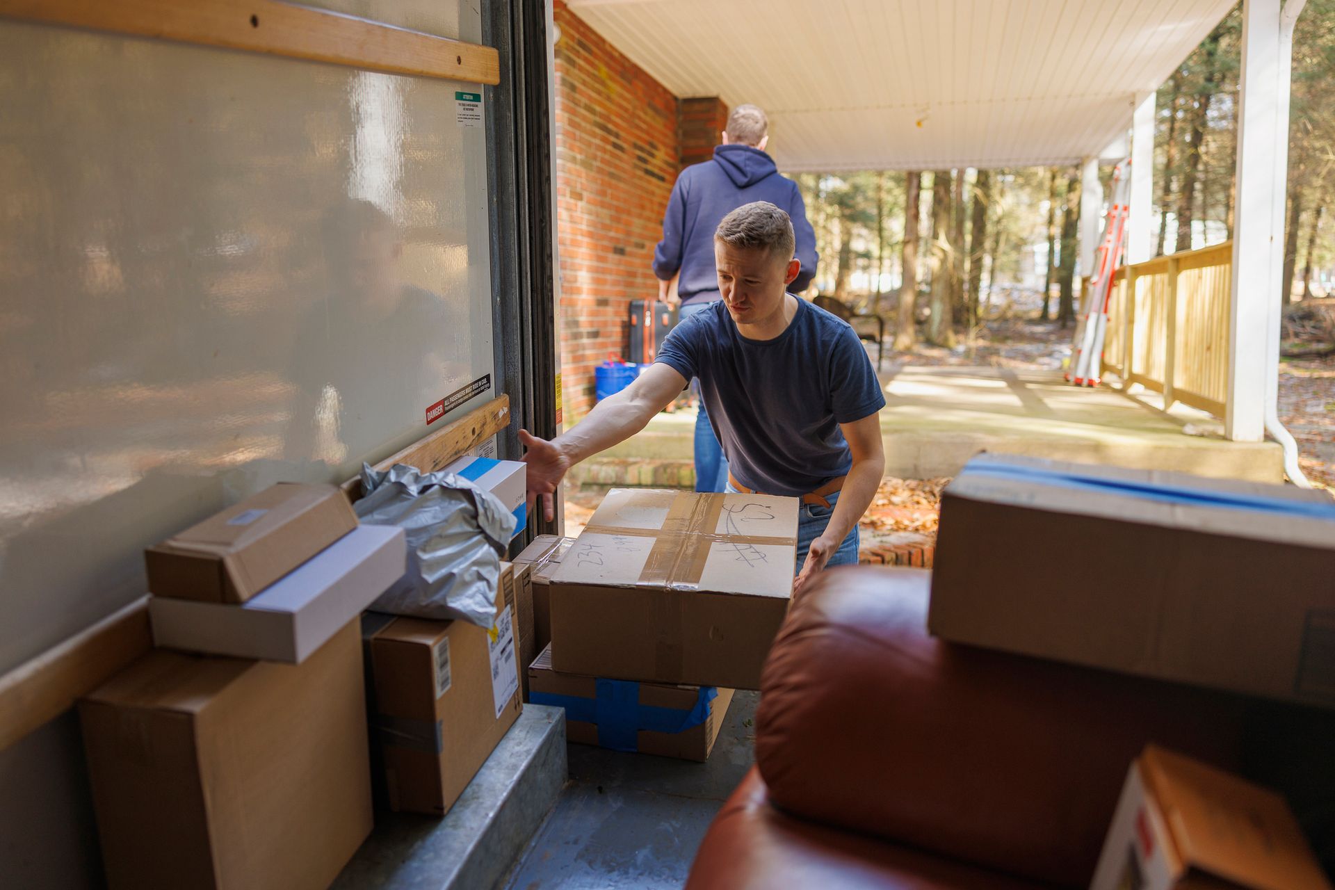 Two men unloading boxes from truck.