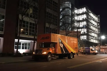 Moving company truck parked outside a commercial building at night.
