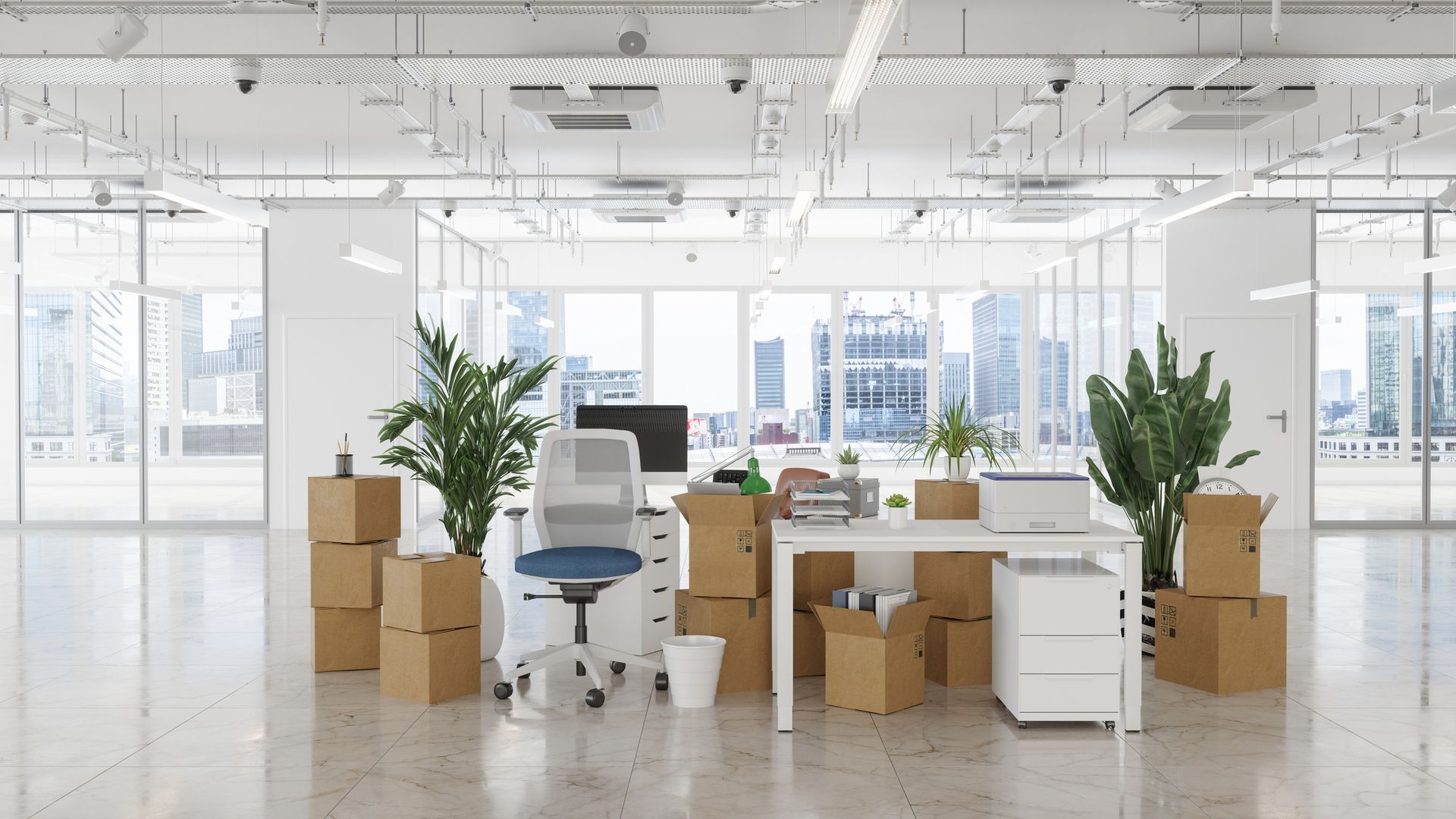 A modern office with boxes, plants, and furniture packed for moving