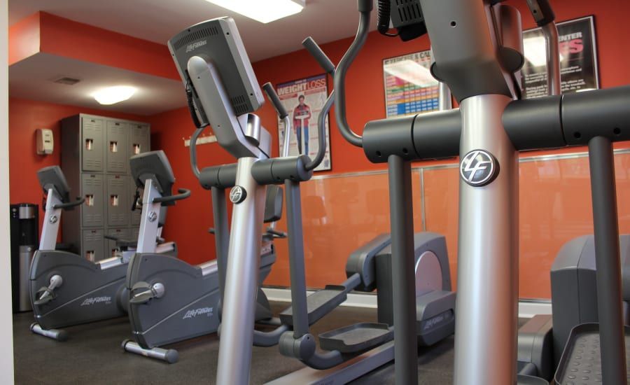 A gym with a lot of exercise equipment including ellipticals and treadmills at Westgate Apartments & Townhomes in Manassas, VA.