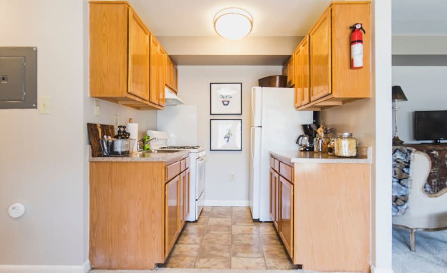 A kitchen with wooden cabinets and a white refrigerator at Westgate Apartments & Townhomes in Manassas, VA.