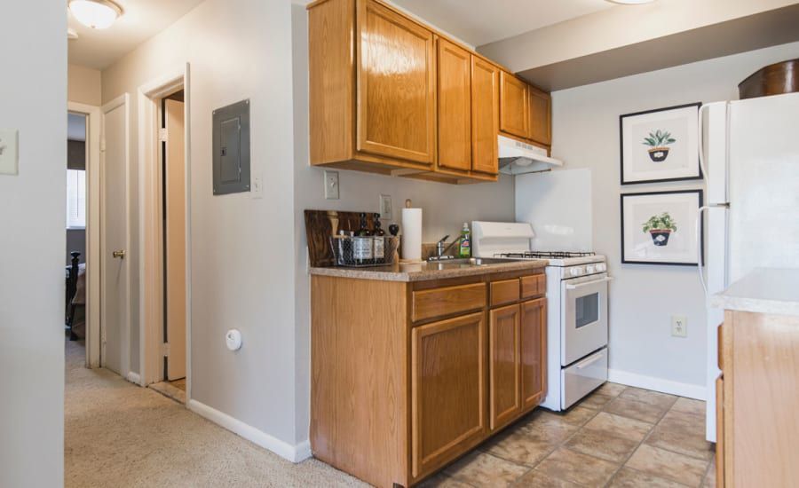 A kitchen with wooden cabinets , a stove , refrigerator and sink at Westgate Apartments & Townhomes in Manassas, VA.