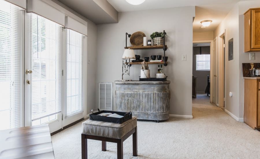 A living room with a sliding glass door and a tray on the ottoman at Westgate Apartments & Townhomes in Manassas, VA.