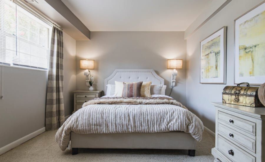 A bedroom with a bed , nightstand , and window at Westgate Apartments & Townhomes in Manassas, VA.