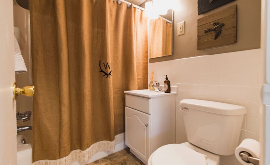 A bathroom with a toilet , sink , and shower curtain at Westgate Apartments & Townhomes in Manassas, VA.