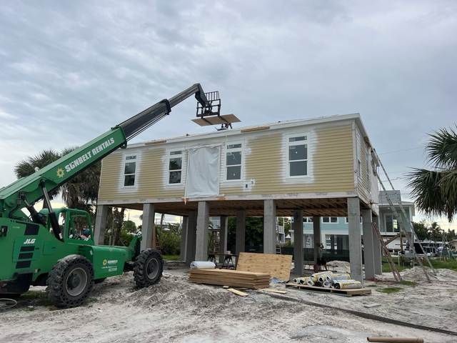 A house under renovation with a green construction lift and workers on the roof.