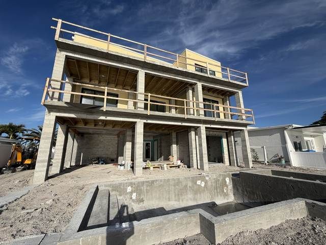 Partially built two-story concrete house with balconies and rubble in the foreground.