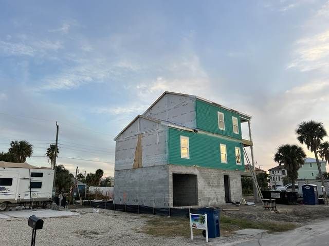 Partially built two-story house with green siding in a residential lot at dusk.