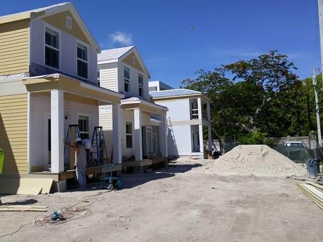 New houses under construction beside a dirt road with a large sand pile.