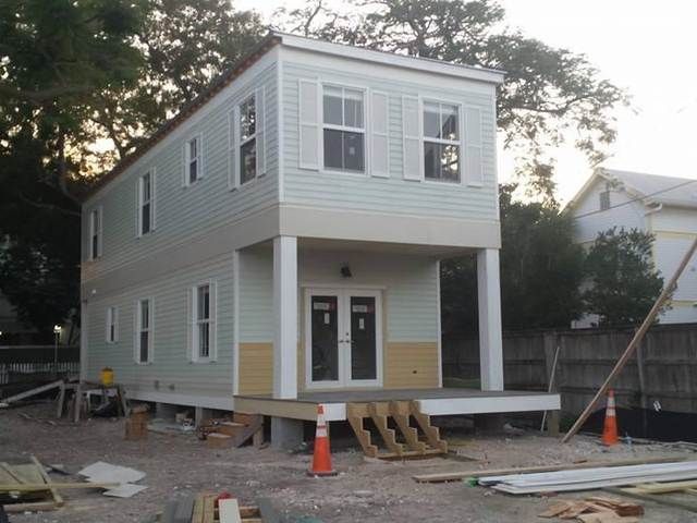 New two-story gray house with white trim under construction, with porch steps and building materials around it.