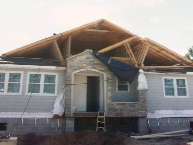 Partially renovated house with exposed wooden roof beams and construction materials at the front entrance.