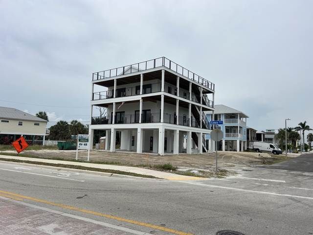 Partially built three-story concrete building at a street corner under an overcast sky.