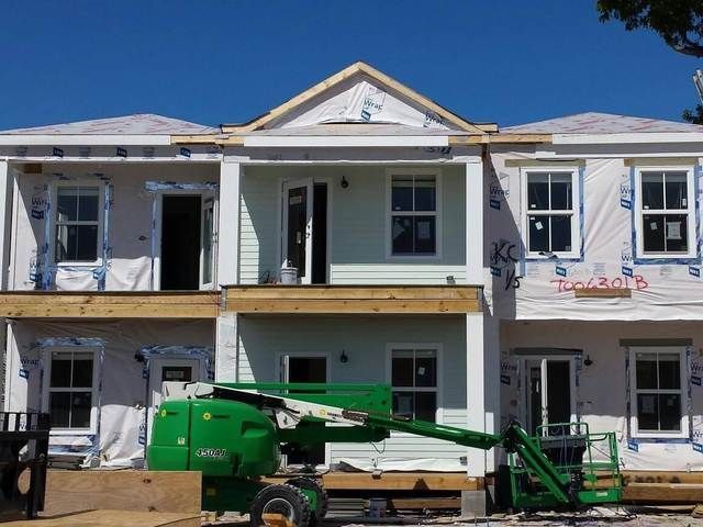 Two-story house under construction with workers’ lift and exposed framing on the front porch.
