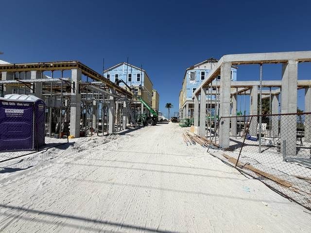 Dusty street between unfinished building frames under a bright blue sky.