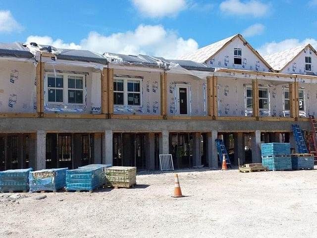 Partially built two-story row of houses with exposed framing and construction materials in front.