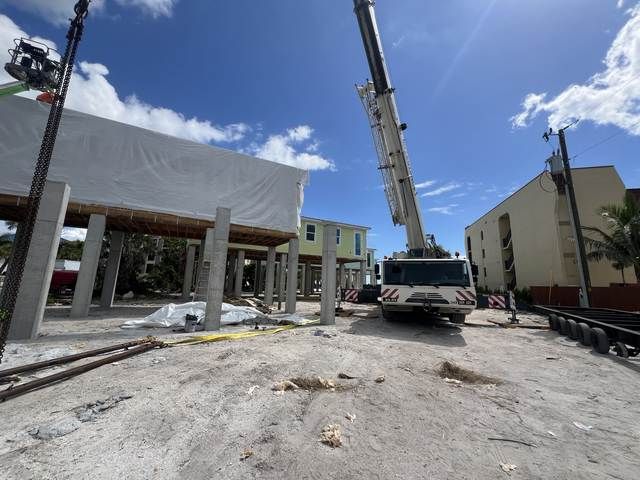 Construction site with a crane lifting a beam beside a partially built building under a blue sky.