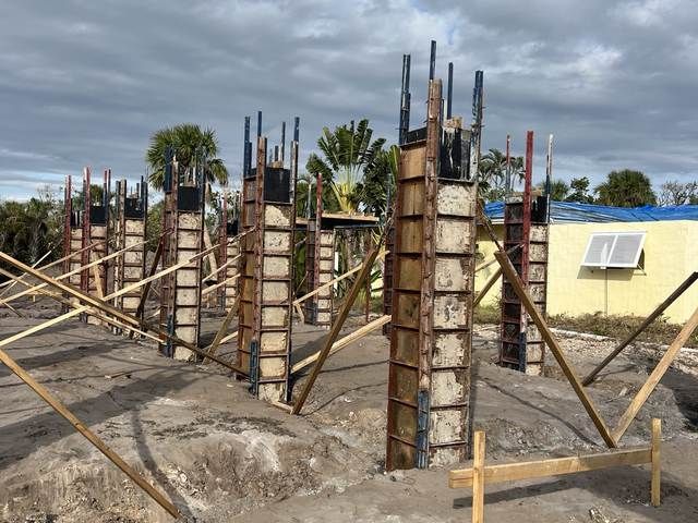 Concrete columns with rebar and wooden braces under construction on a sunny site.
