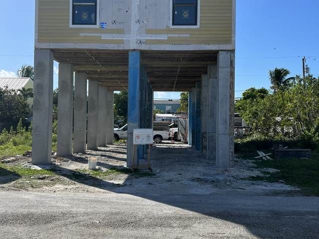 Concrete underpass beneath a building with a dirt path and a parked vehicle in the distance