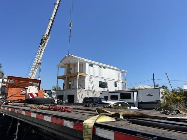 House under construction beside a crane under a clear blue sky.