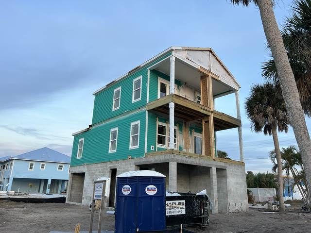 Partially built green house with exposed concrete floors and a blue portable toilet in front.