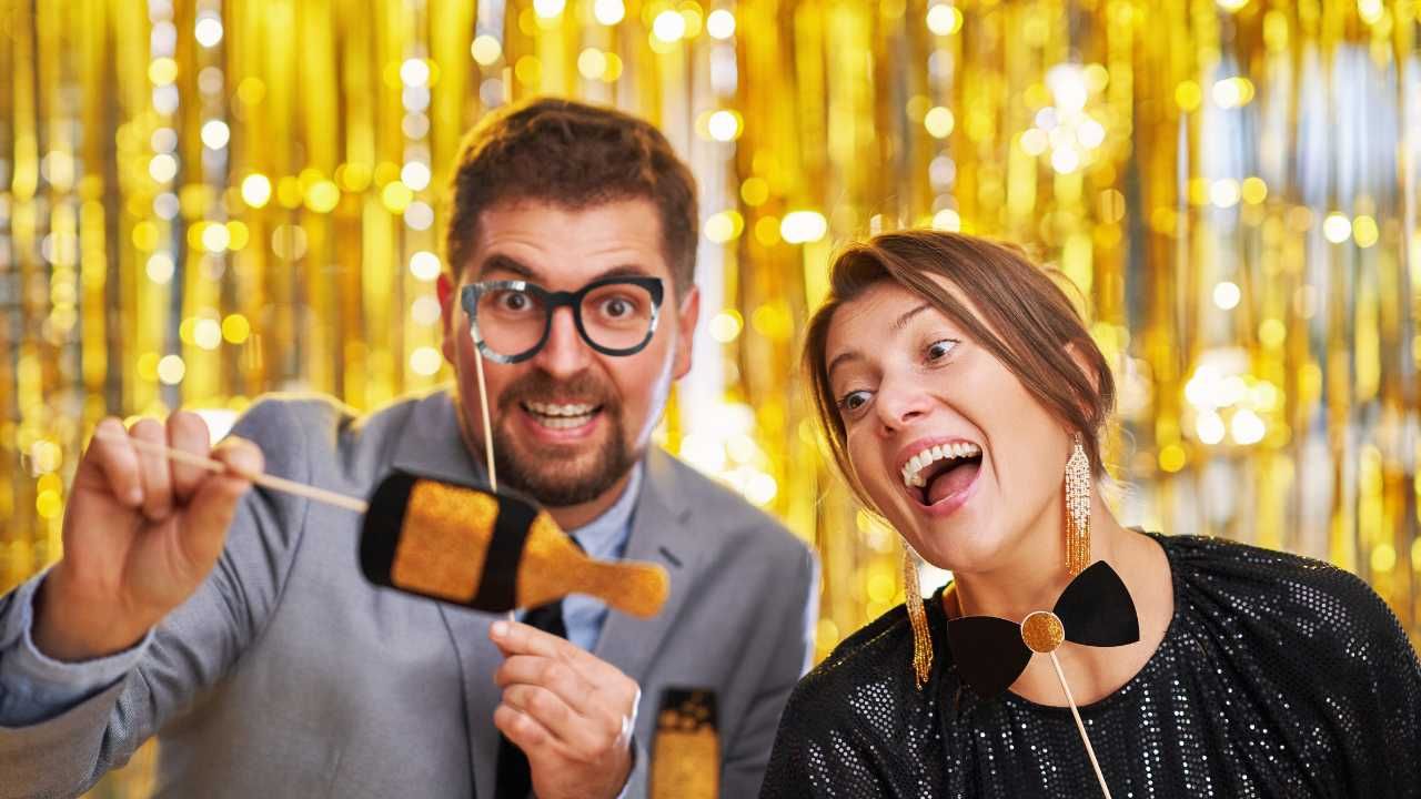 A man and a woman are holding a bottle of champagne on a stick.