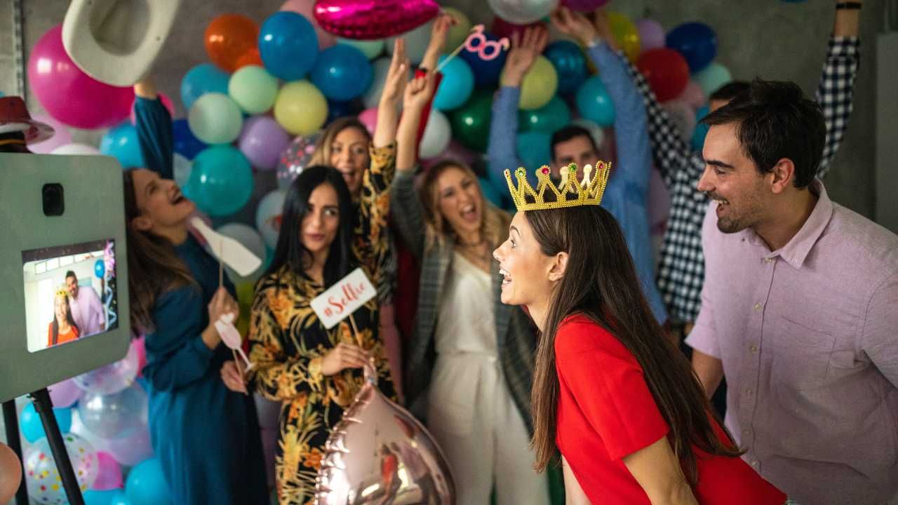 A group of people are posing for a picture at a party with balloons.