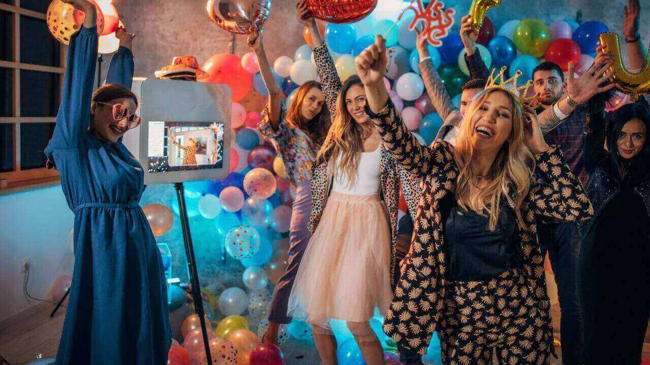 A group of people are standing in front of a wall of balloons at a party.