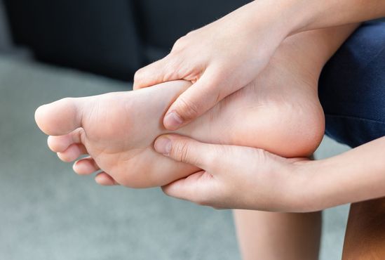 Hands holding and examining a foot, possibly due to pain or injury.