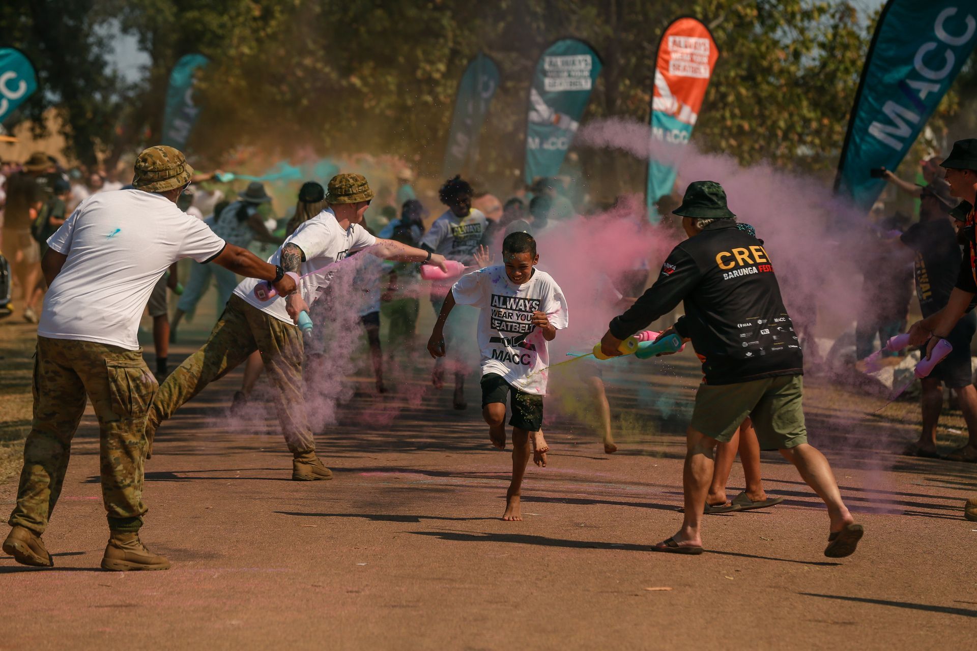 A group of people are playing with colored powder in a park.