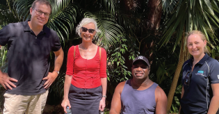 A group of people standing next to each other in front of a palm tree.