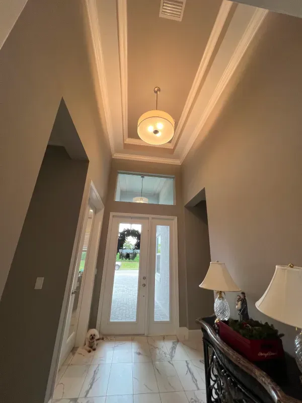 A foyer with a chandelier, white double doors, and beige walls.