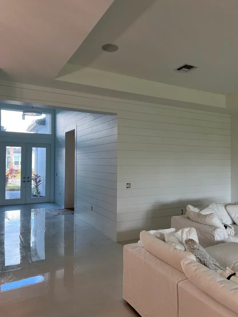Bright white interior with shiplap wall, glass doors, and a white sofa.
