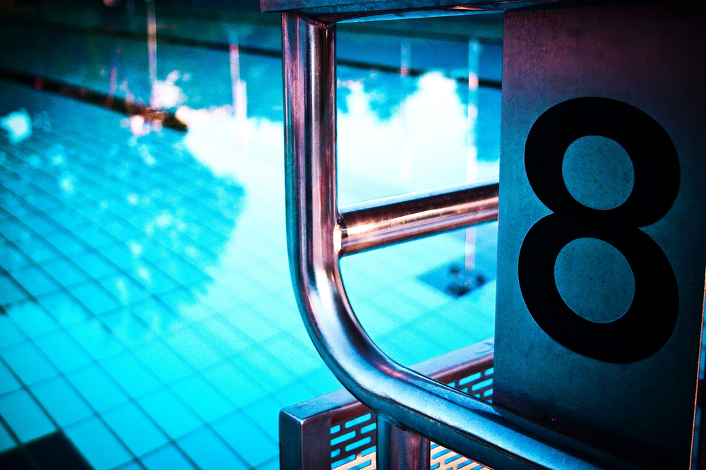 A swimming pool with the number 8 on the side of the diving block.