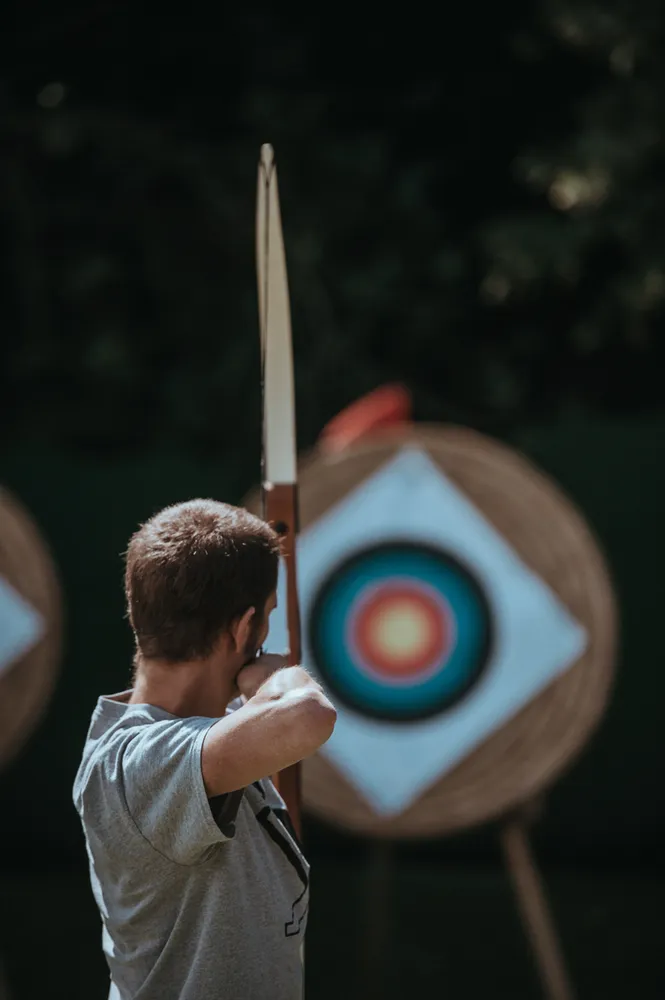 A man is aiming a bow at a target.
