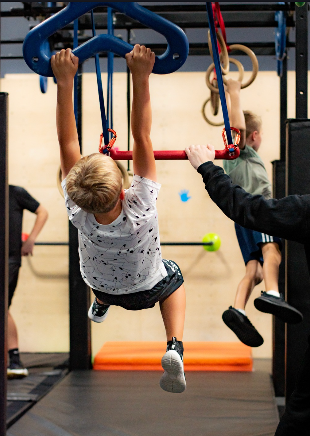 Children hanging from gym rings in an indoor obstacle course