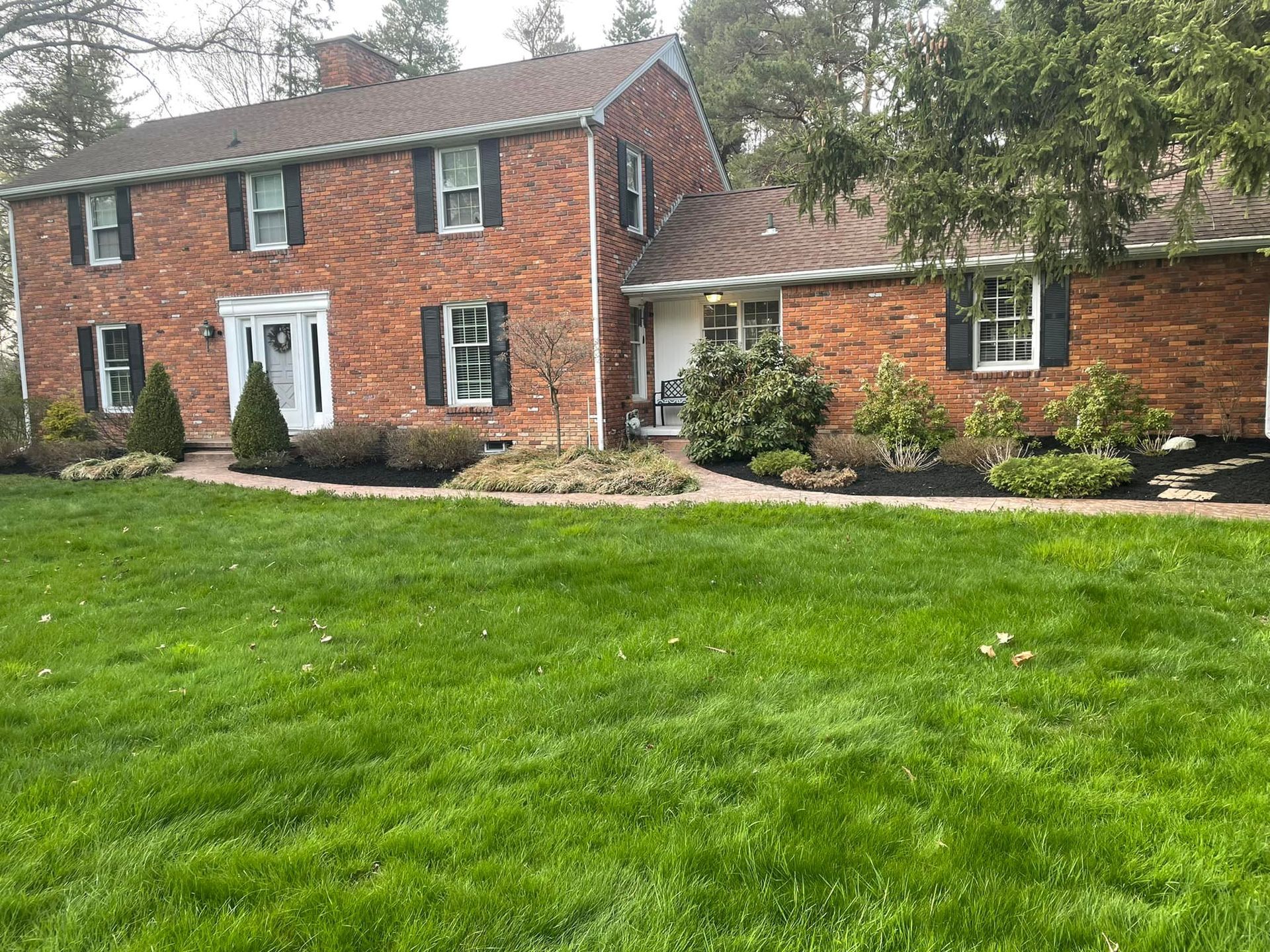 A Large Brick House With A Green Lawn — Orchard Park, NY — Battles Landscaping and Lawn Service
