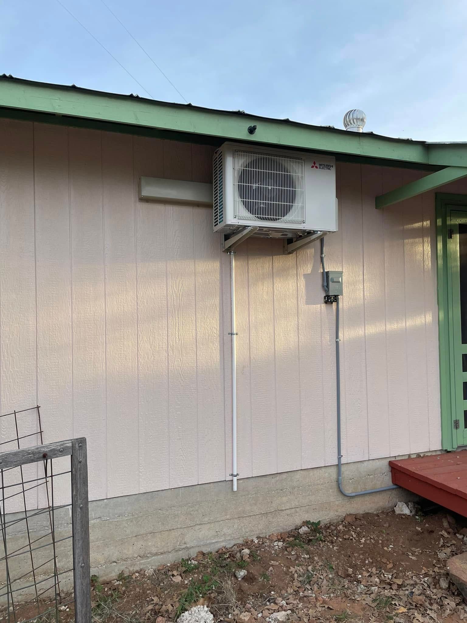 Exterior wall with air conditioning unit mounted on it, along with electrical conduit.
