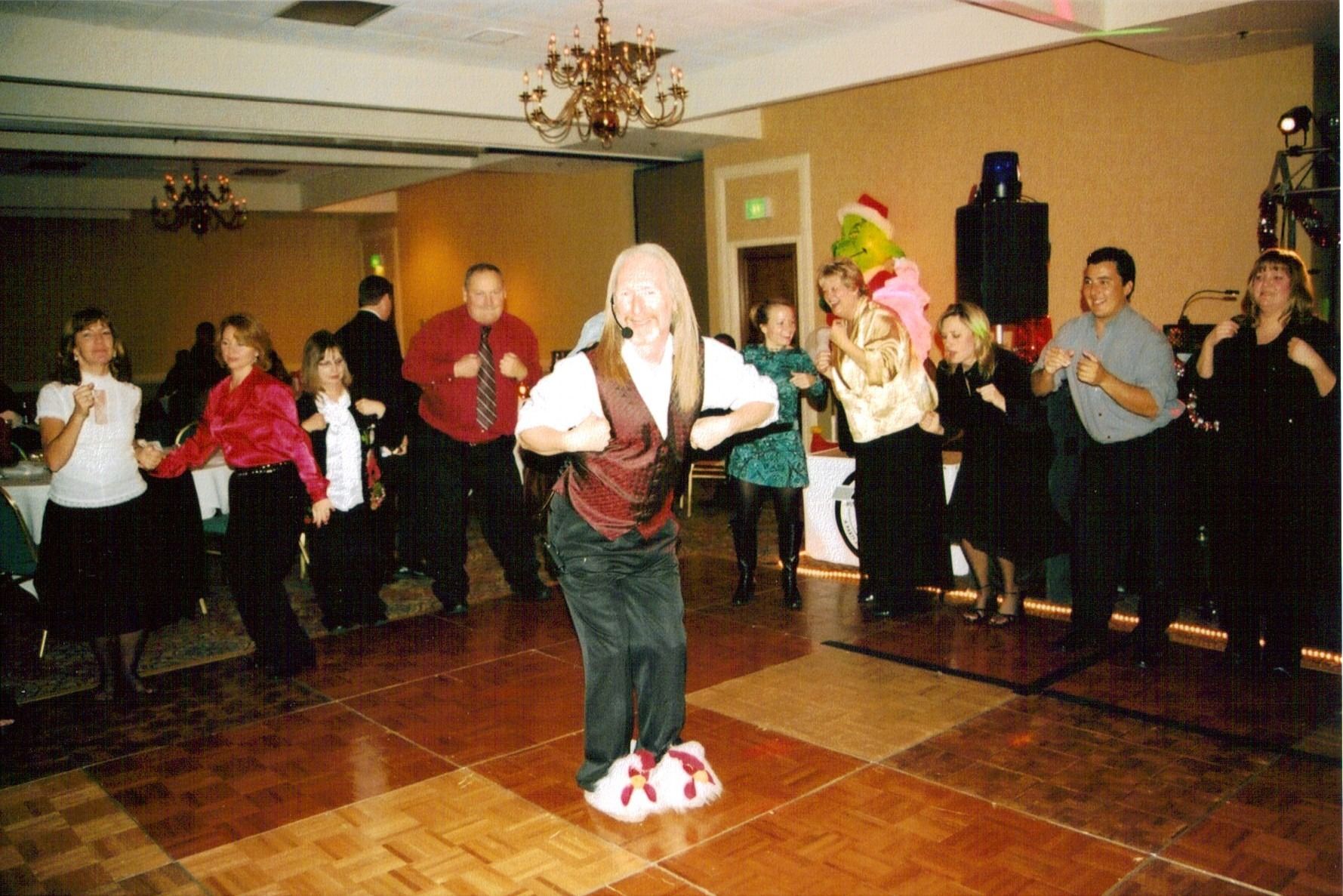 People dancing in a banquet hall with a tiled floor and guests watching along the walls