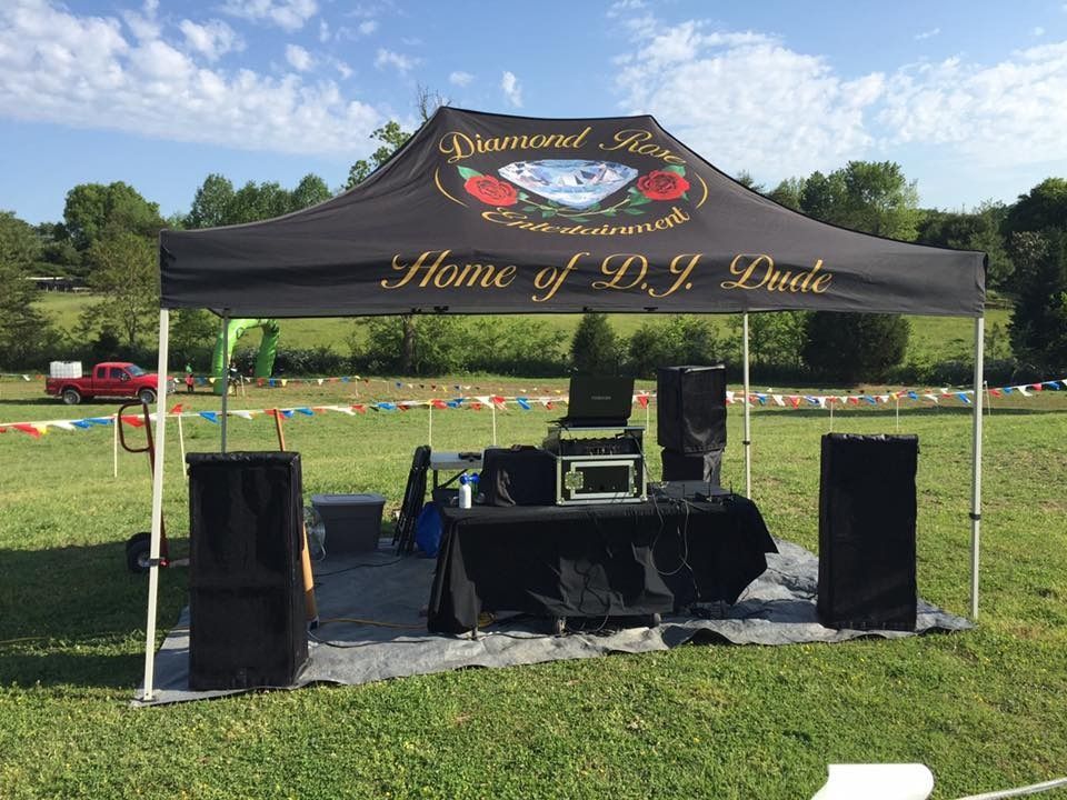 Black event tent with speakers and stage setup on a grassy field, branded “Home of R.J. Drake.”