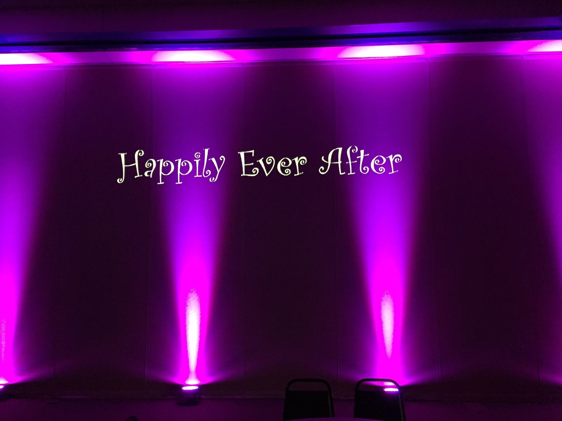 Purple-lit wall with the words “Happily Ever After” projected on it.