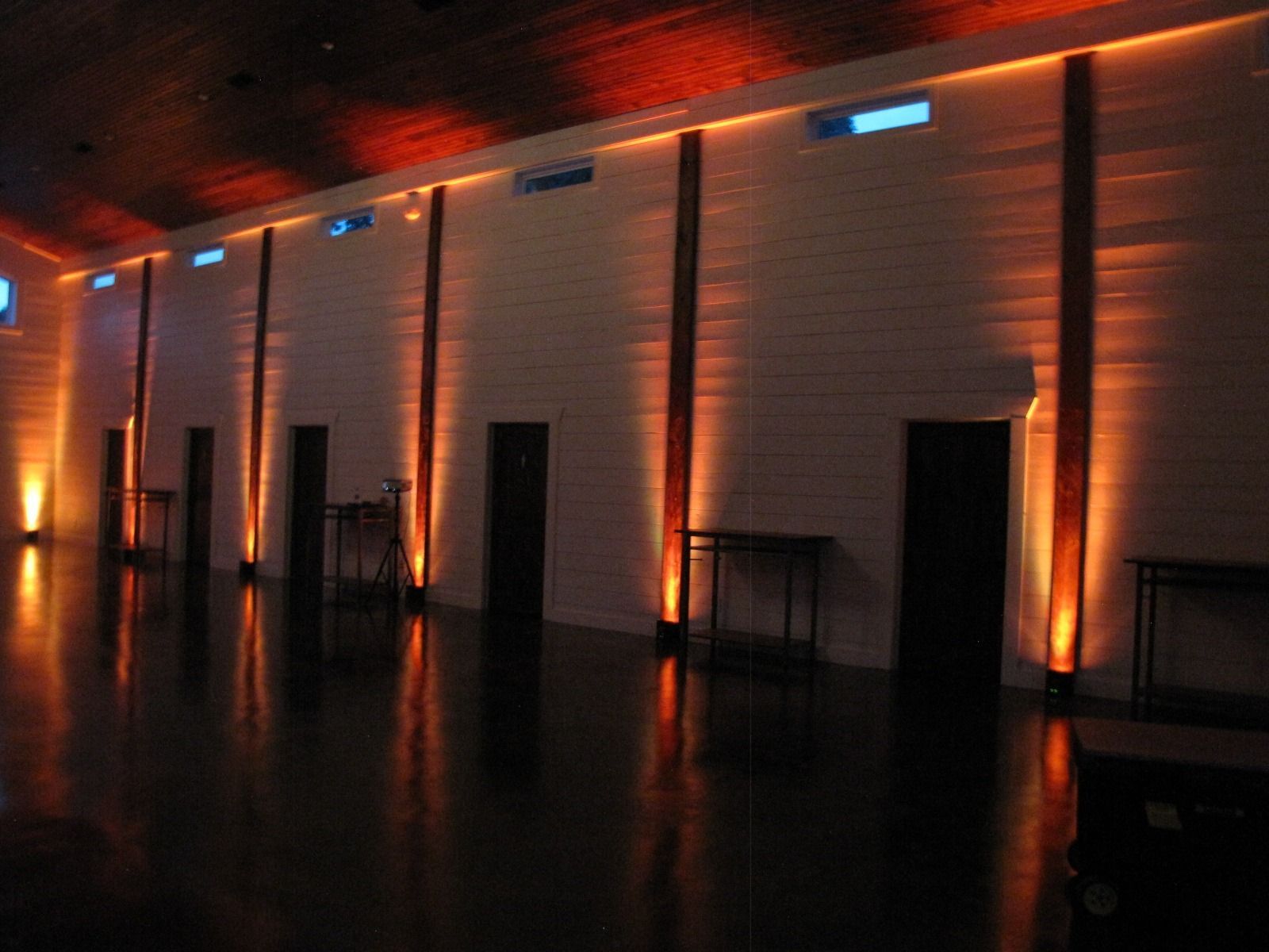 Dimly lit hall with warm orange wall lights and a glossy black floor