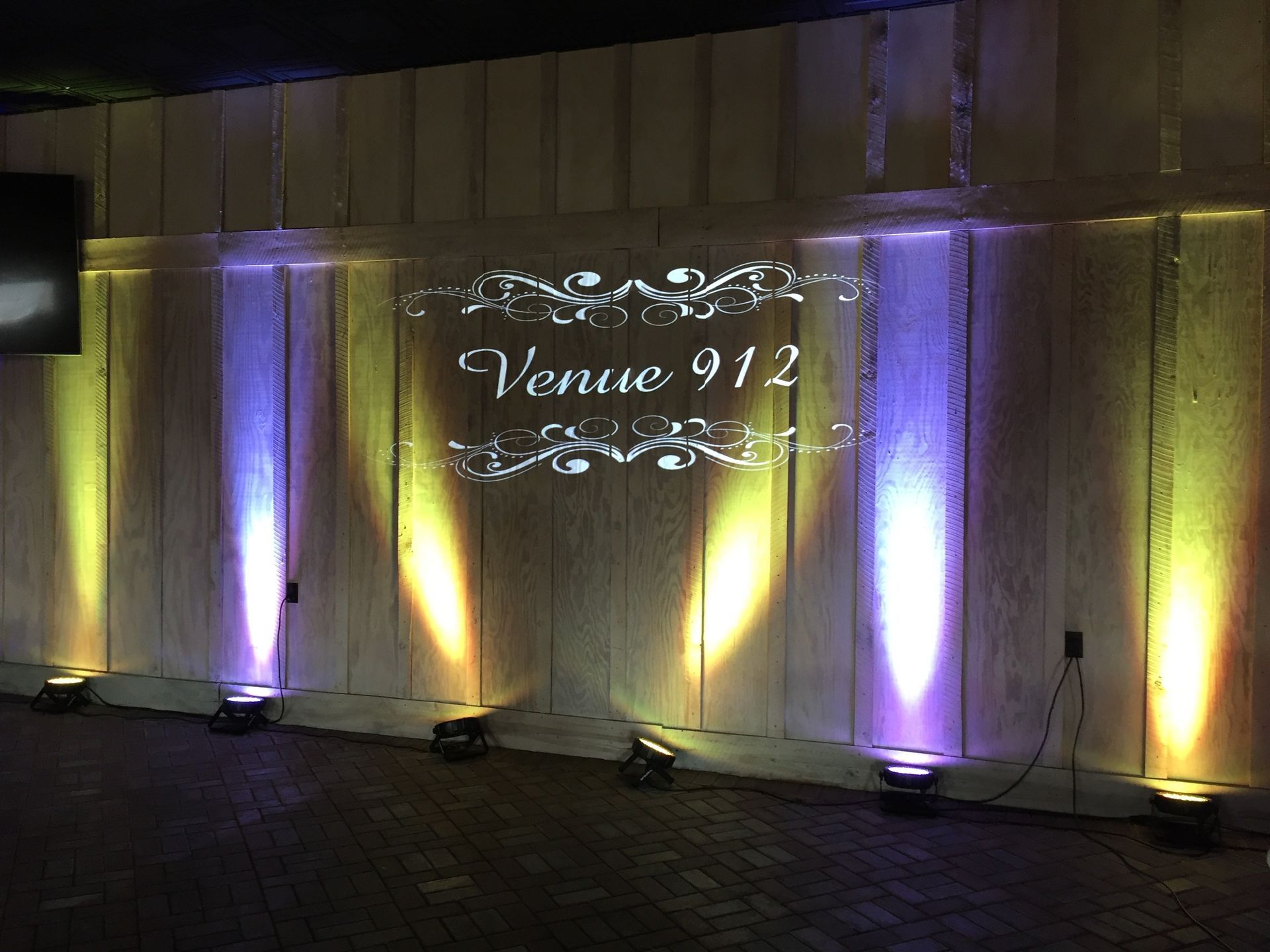 Lit wall with purple uplights and projected “Venue 912” sign at an event entrance