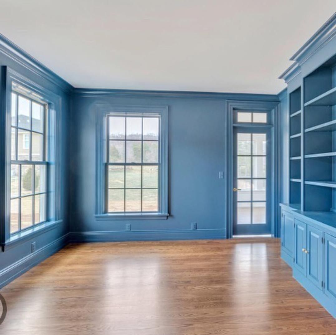 An empty room with blue walls and hardwood floors.