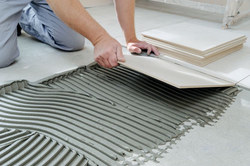 A person is laying tiles on a tiled floor.