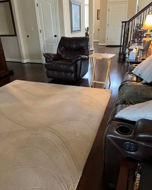 A living room with a couch , chair , table and rug.