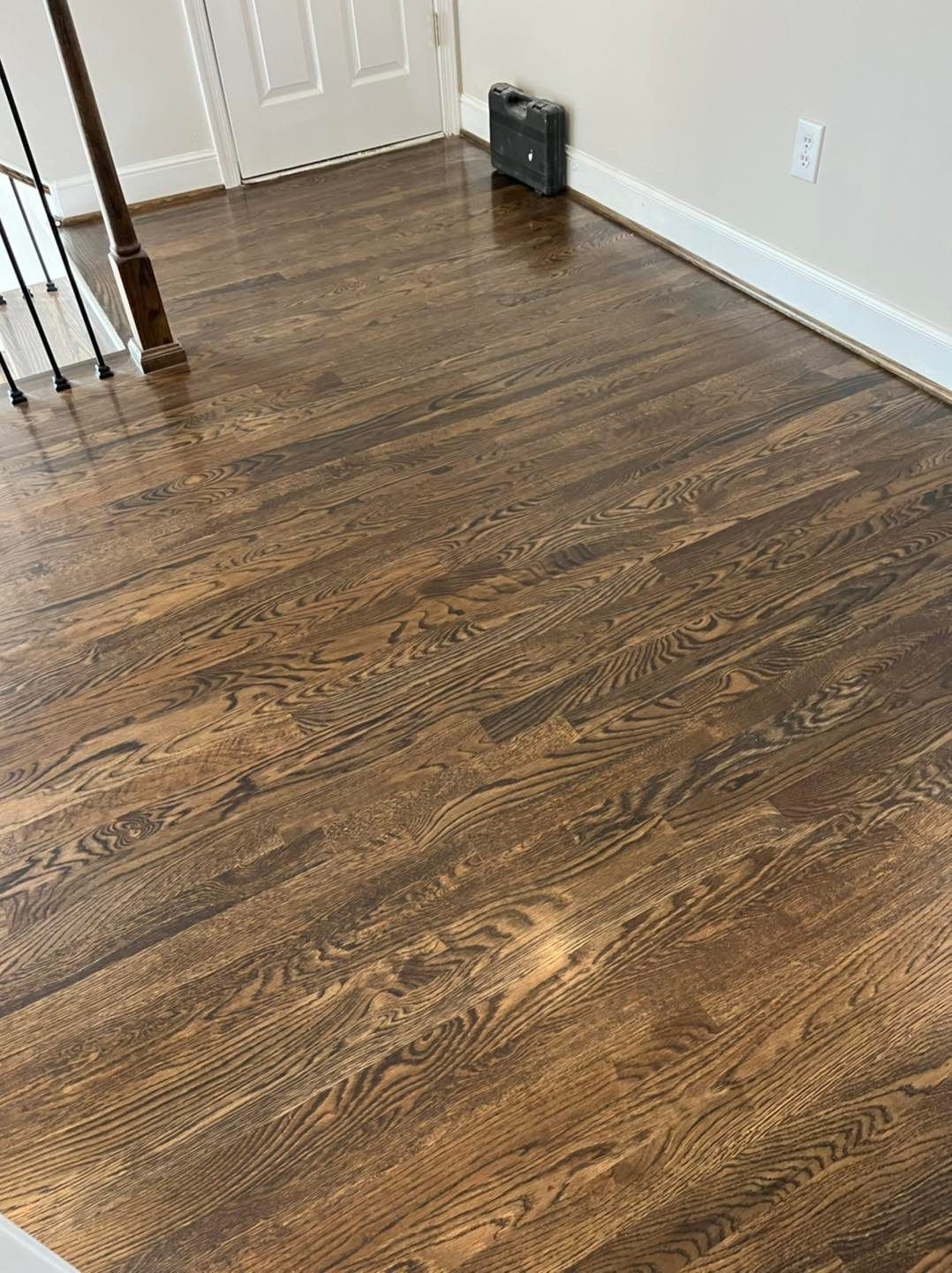 A wooden floor in a living room next to a staircase.