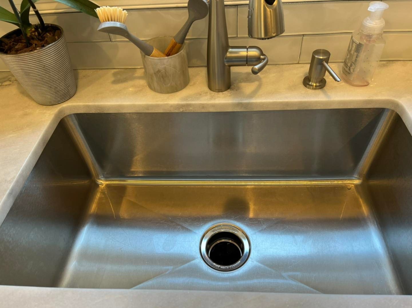 A stainless steel kitchen sink with a faucet and soap dispenser